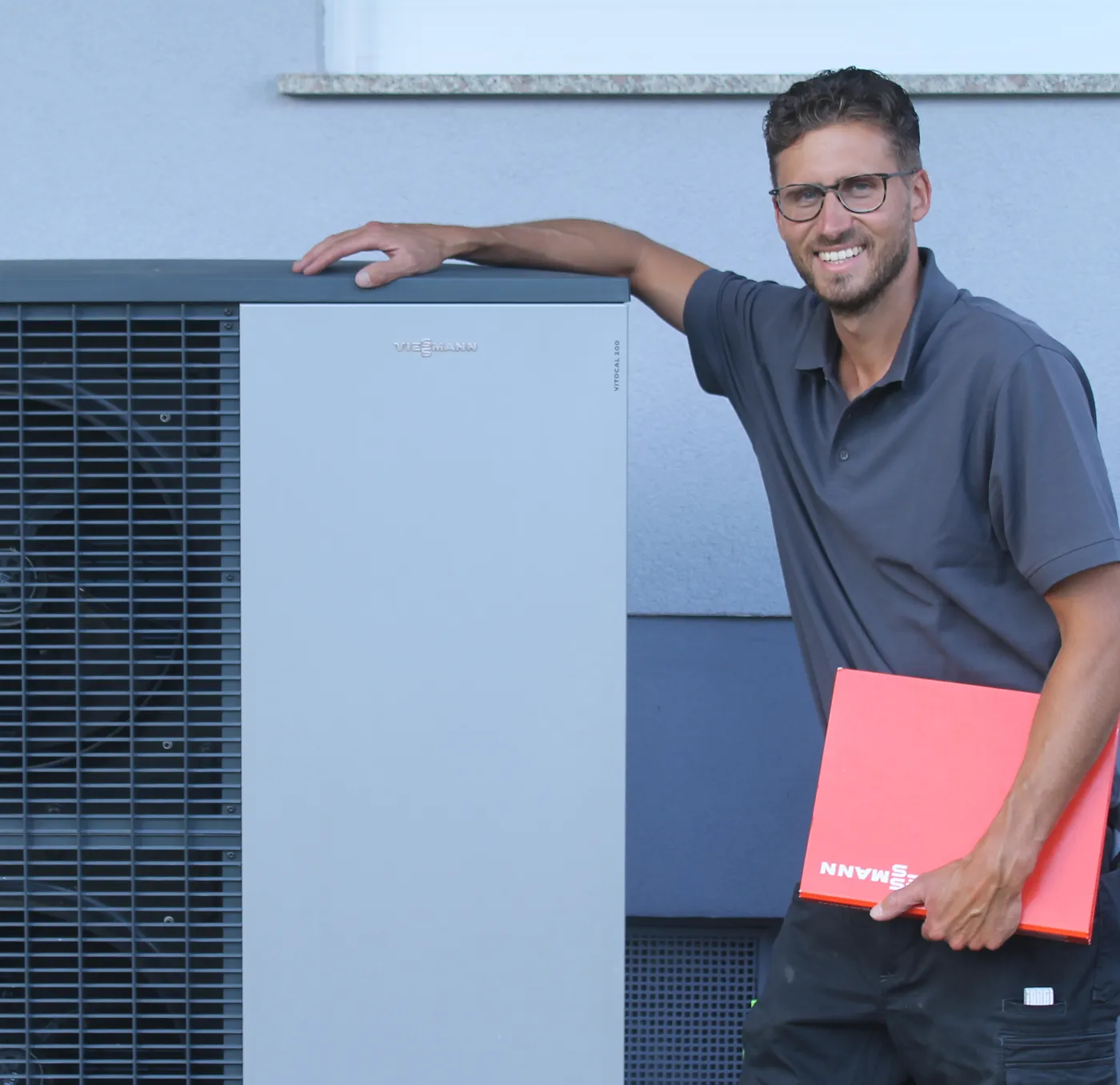 Jan Roth an einer fertig montierten Viessmann Wärmepumpe an der Hauswand